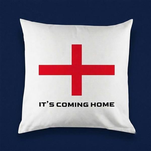A square white cushion cover featuring the St George's Cross flag and the printed text It's Coming Home, displayed against a solid dark blue background.