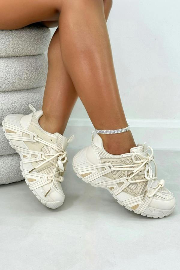 Beige sneakers worn by a person sitting on a gray cushioned chair.