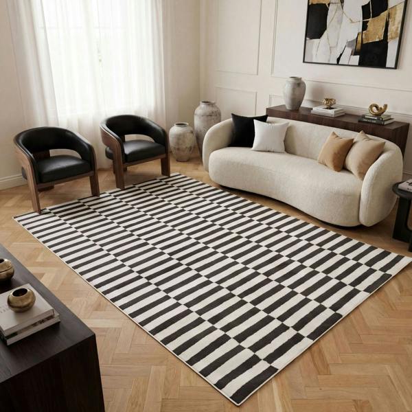 Living room with a black and white striped rug, beige sofa, and modern decor.