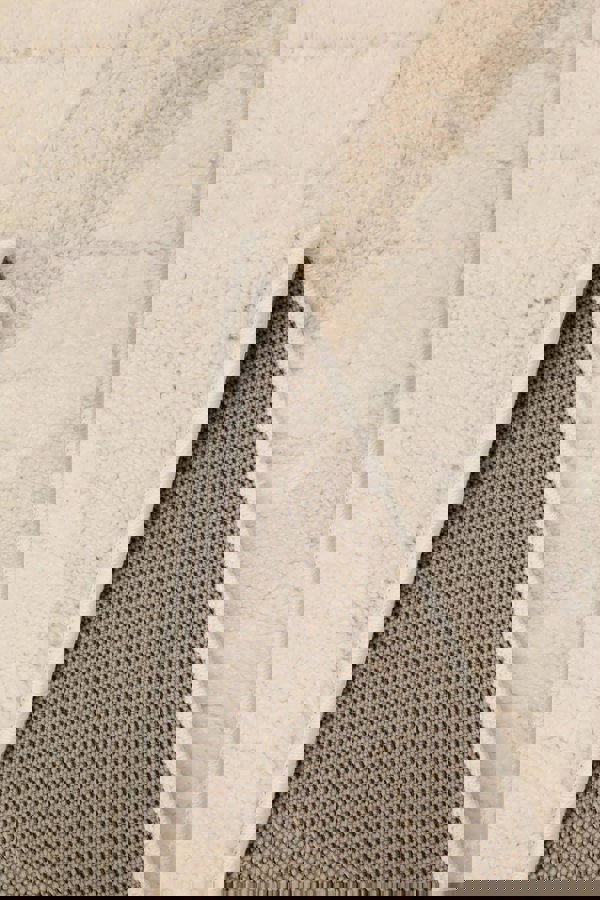 Close-up of Ava Pave Wave Illusion Rug's cream abstract texture and backing, highlighting its soft and durable fabric.
