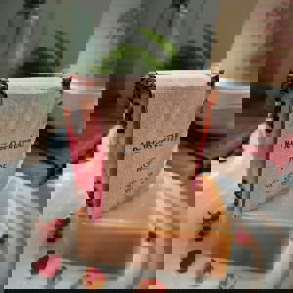 Bar of soap with 'Ralph's Orchard' branding on a white plate with rose petals.