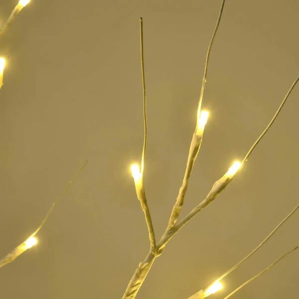 Close-up of artificial birch branches with warm white LED lights glowing on tips