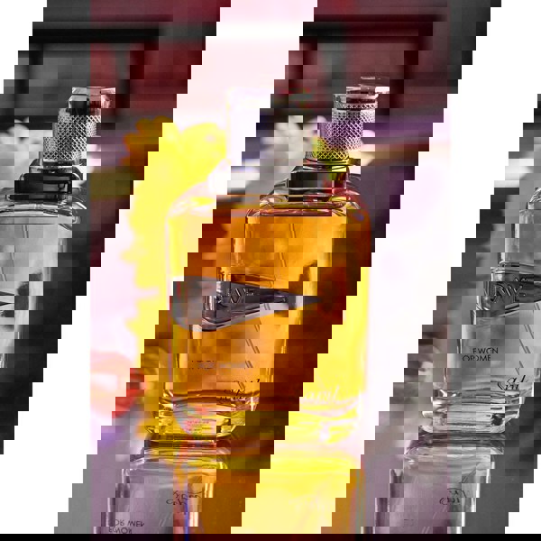 Rave Women Eau de Parfum bottle in vibrant orange light