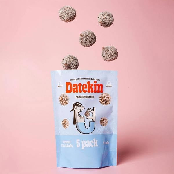 Datekin coconut round date balls packaging with balls spilling out on a pink background