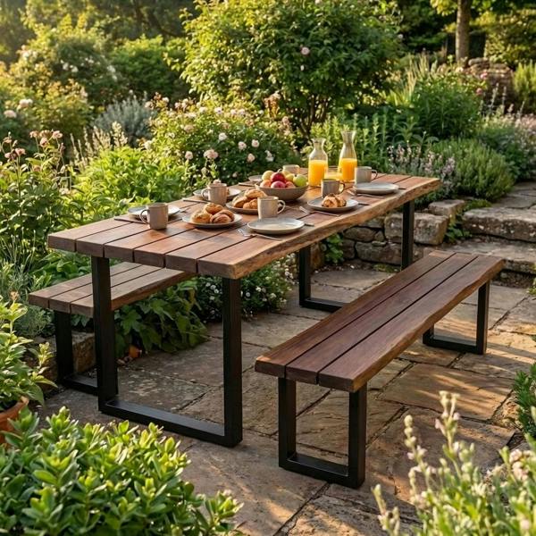 Wooden outdoor table with benches set in a garden with food and drinks.