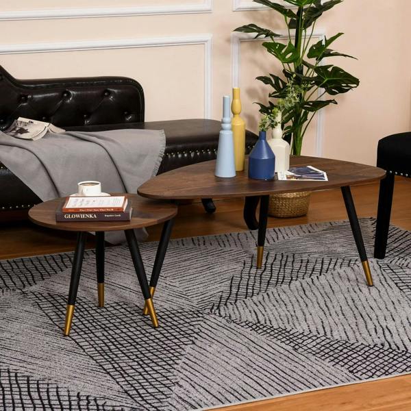 Two walnut round coffee tables with black legs and gold accents beside sofa