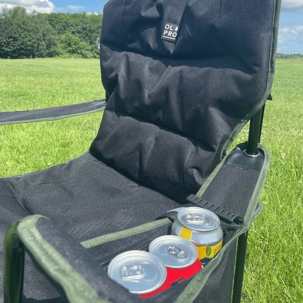 An image of a can of pop being stowed in the can holder of the Henwick Padded Folding Camp Chair - Black & Green from OLPRO outside of a tent.