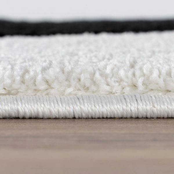 Close-up of a white rug with a textured surface on a wooden floor.