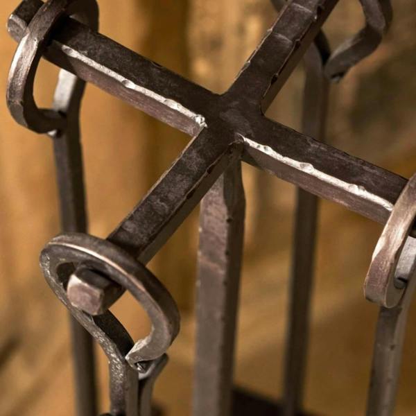 Close-up overhead view of the cross-shaped top stand and textured ironwork on the antiqued brown fireside companion set.