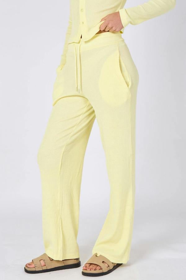 Person wearing a light yellow outfit with pants on a white background