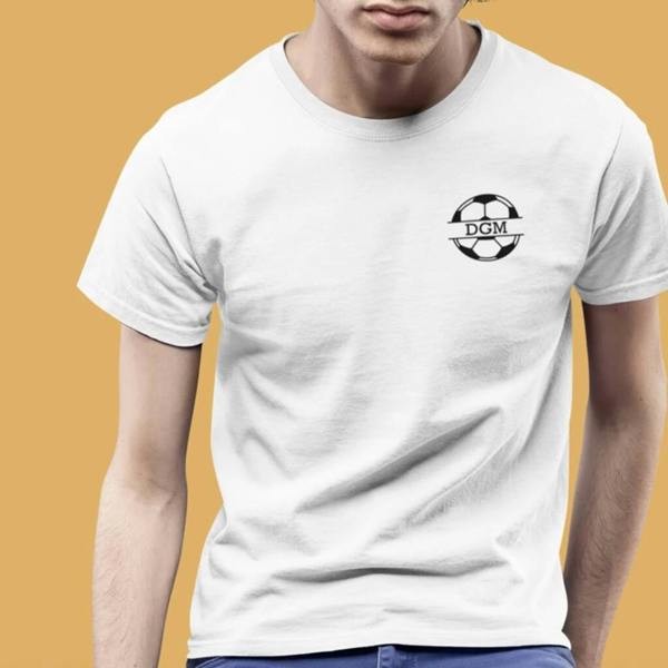 A man wearing a white unisex t-shirt featuring a black football logo on the left chest. The football design is personalised with the initials "DGM" inside a central banner, set against a mustard yellow background.