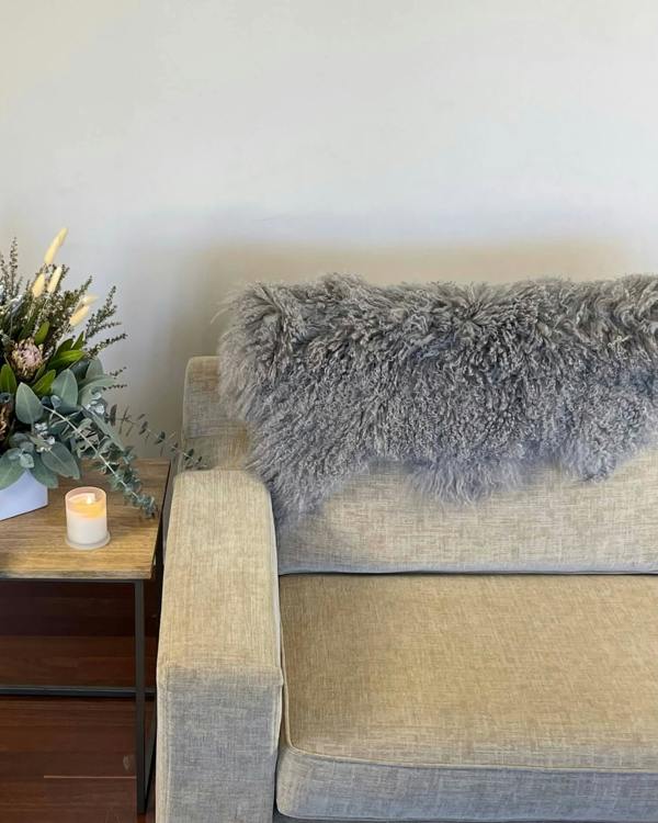 Grey Mongolian Sheepskin Rug draped on back of sofa