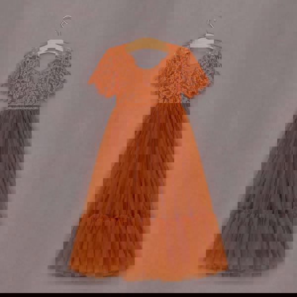 Orange lace dress on a hanger against a gray background