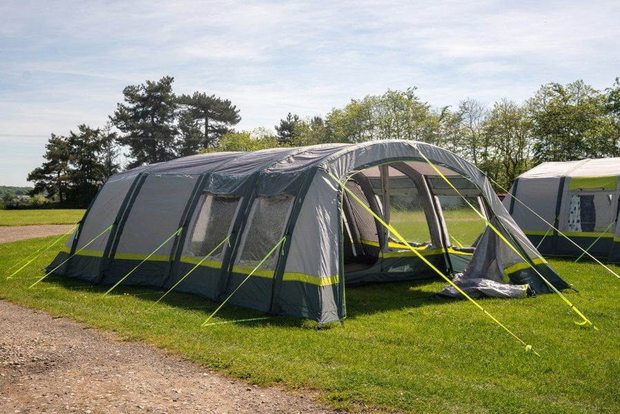 The OLPRO Odyssey  Breeze® Inflatable 8 Berth Tent pitched in a campsite with a treeline in the background.