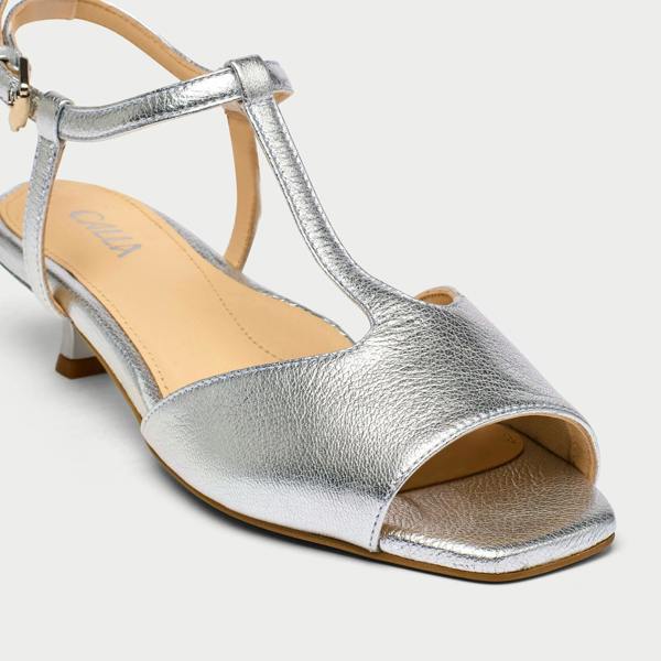 Silver sandal with open toe and T-strap design on a light gray background