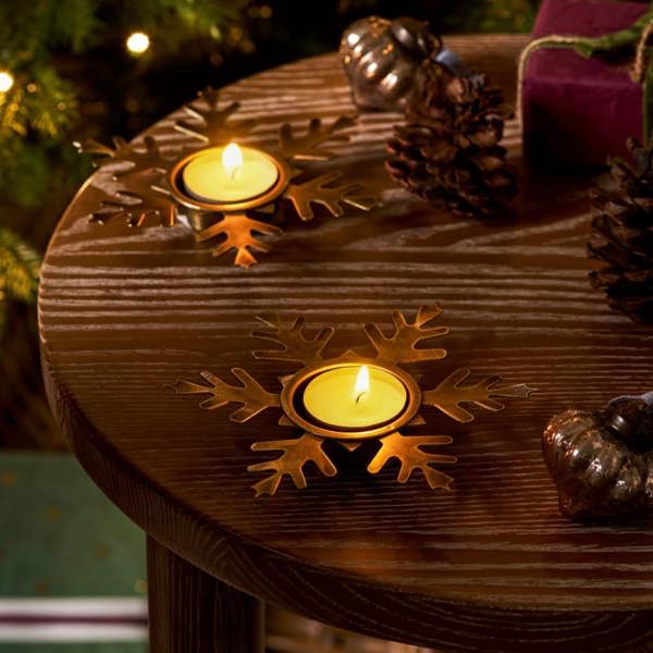 Two snowflake-shaped antique brass tealight holders on a festive table.