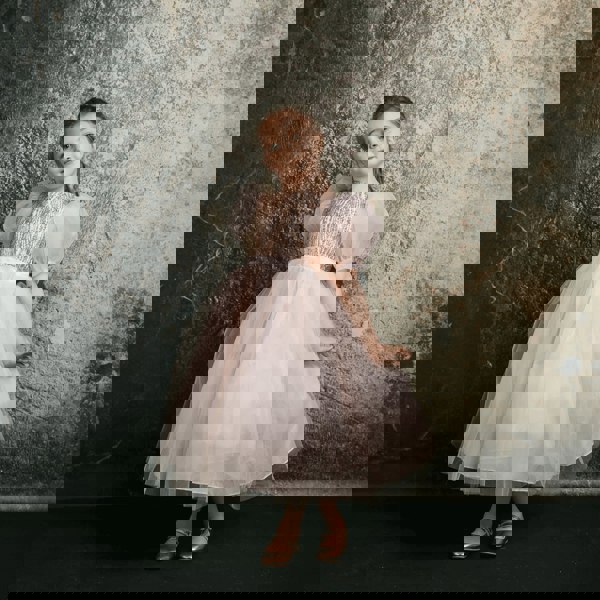 Dark haired girl wearing a blush coloured party dress from UK Flower Girl Boutique