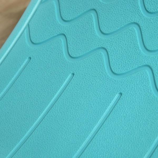 Close-up of teal wobble board tread texture with raised zigzag grips on the surface.