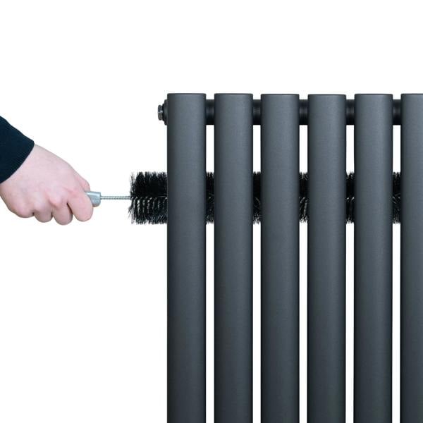 Anthracite grey oval single column radiator being cleaned with a brush, showcasing its sleek, modern design and smooth texture