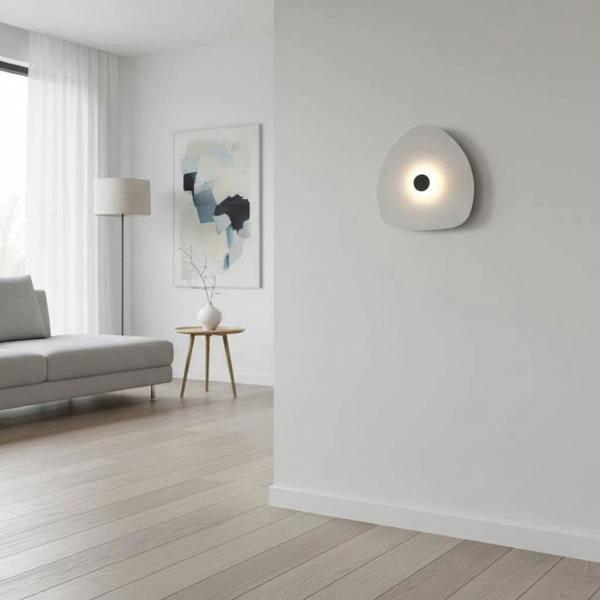 Modern internal wall light with a white finish and a black central halo on a wall within  a modern lounge