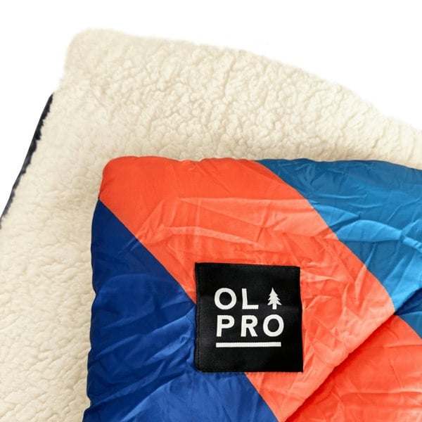 A close up of the Sherpa fleece lined fabric, alongside the Durable Water Resistant Polyester of the Limited Edition OLPRO Ocean Sunset Blanko