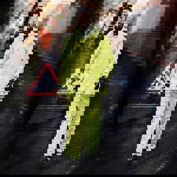 Scruffs Mens Waterproof Suit Yellow Two-Piece Rain Set Rainsuit Trousers and Jacket, a man wearing bright yellow waterproof rain suit walking outdoors on a wet pavement.