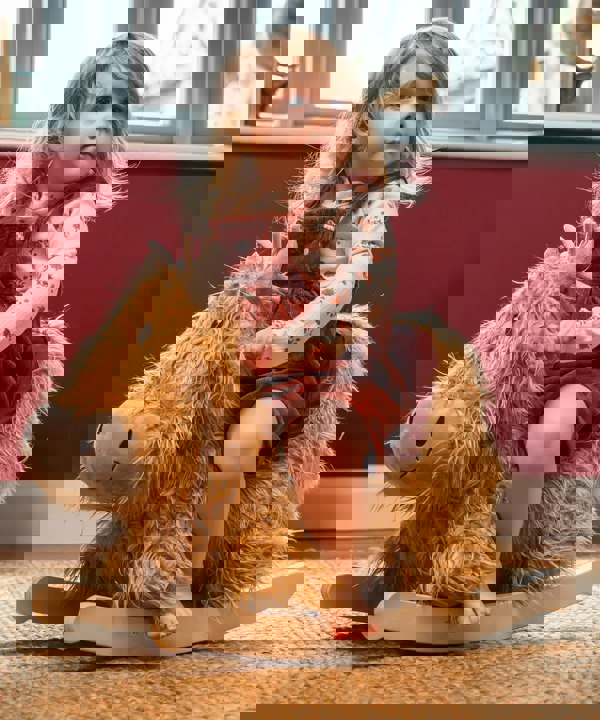 Little girl sitting on a highland cow rocker