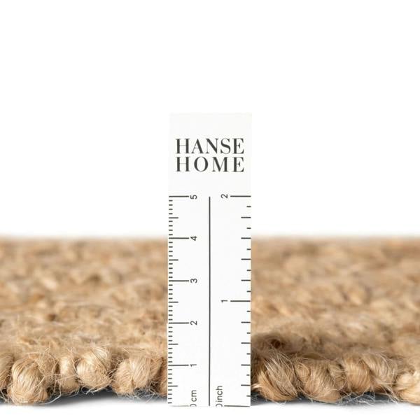 Close-up of a textured rug with a ruler and 'HANSE HOME' branding.