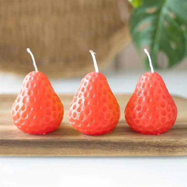 Set of three strawberry-shaped red candles with white wicks