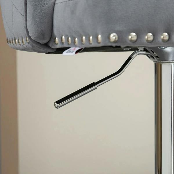 Close-up of grey velvet bar stool with nailhead trim and chrome height-adjust mechanism