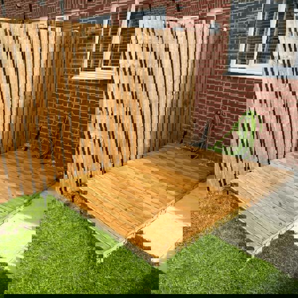 Wooden deck in backyard next to fence