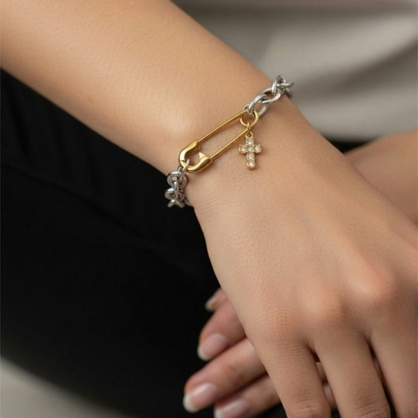 Bracelet with gold and silver charms on a wrist against a neutral background