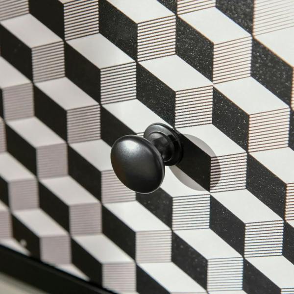 Round black knob on a geometric patterned drawer front in black, white, and gray