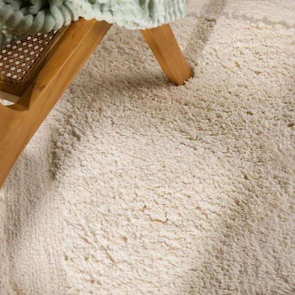 Close-up of a textured beige carpet with wooden furniture legs visible.