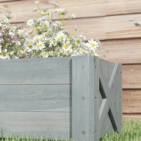 Grey raised planter box corner with small white daisies growing