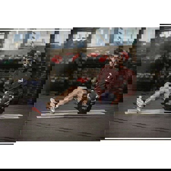 Man sitting on a Reebok 7mm Training Mat in the gym working out with a medicine ball 