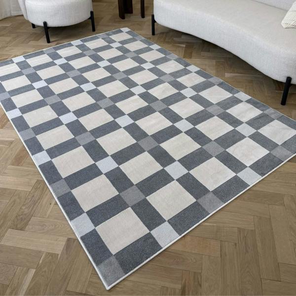Checkered area rug on a wooden floor with a sofa and chair in the background