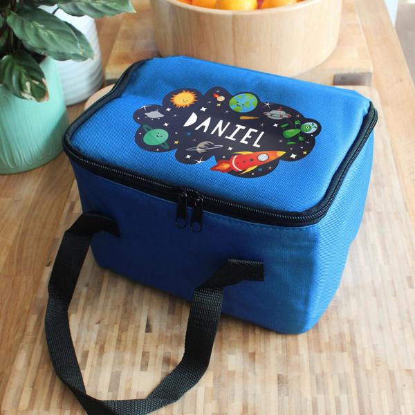 An insulated blue children's lunch bag personalised with the name Daniel, featuring a colorful space cloud design with stars, planets, and a rocket ship.