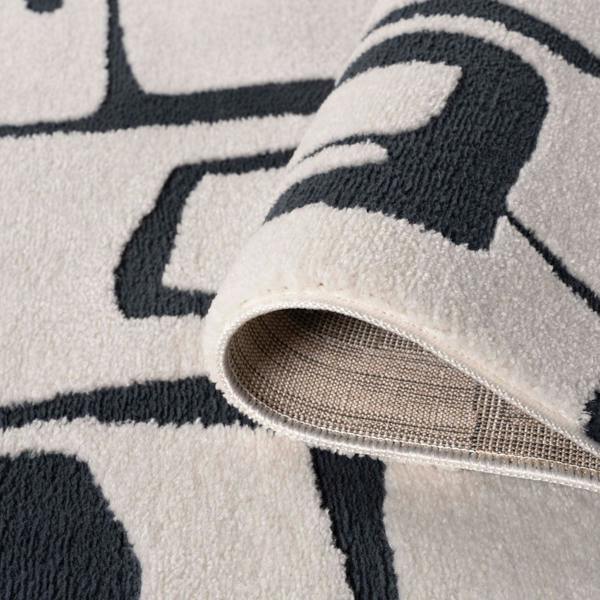 Close-up of a textured rug with geometric pattern and visible backing.