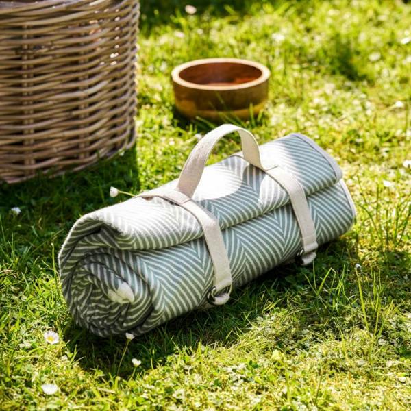 Rosemary green herringbone picnic blanket rolled in a fabric carry harness.