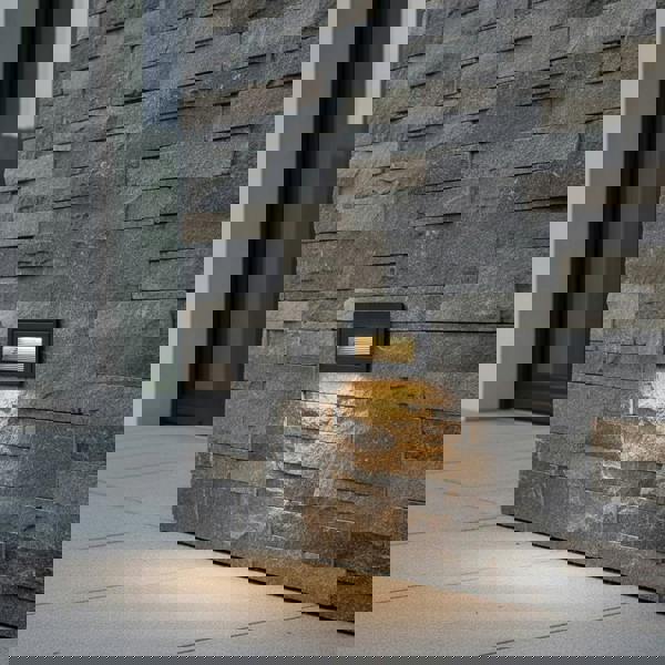 black low level wall light mounted on a stone wall outside of a modern house