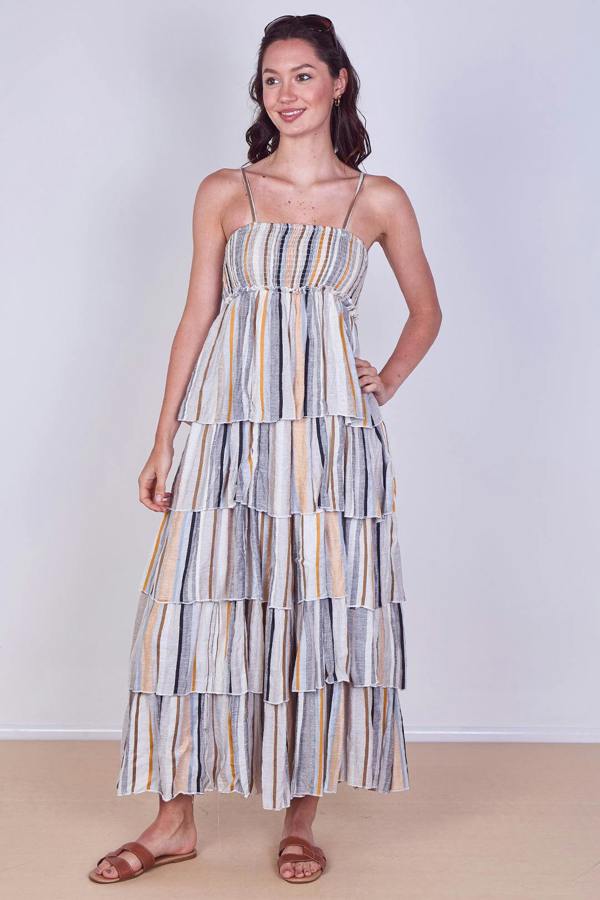 Woman wearing a striped tiered dress against a plain background