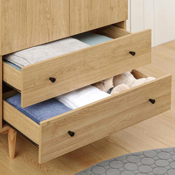 Wood wardrobe drawers with black knobs, open for storing folded clothing