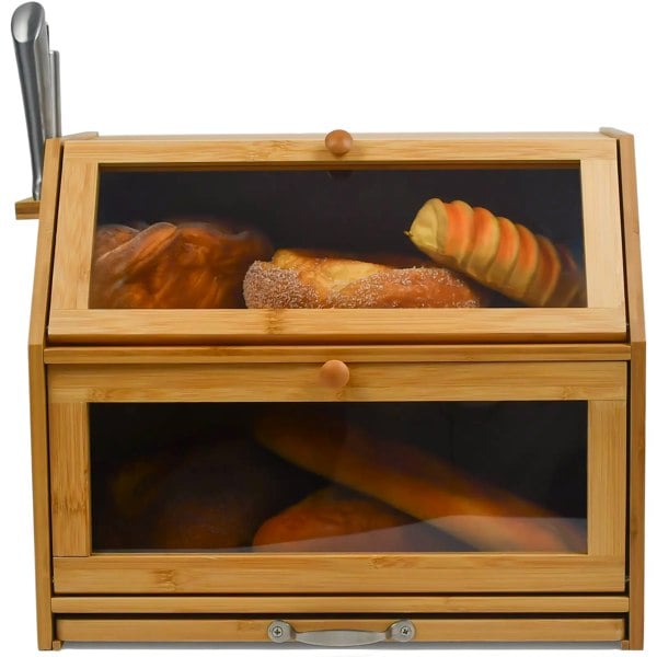 A bamboo bread bin with two compartments and a sliding chopping board, featuring a knife holder. The bread bin has air holes at the back and is displayed with various baked goods inside.