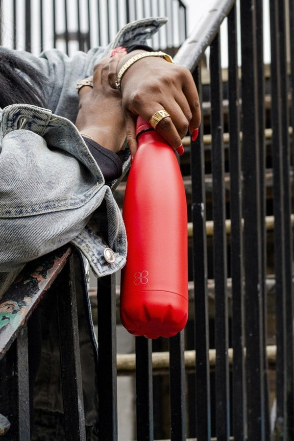 Lady with hand and finger jewellery holding a red drink bottle