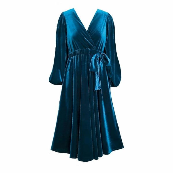 This is a bluey-teal velvet dress silhouetted on a white background. The dress is made off gathered head sleeves to a bell shape bottom and a cross over drop v-neckline. The lower half consists of a sewn in belt decorated with gathers and and tied with a bow which is adjustable. The skirt is attached with gathers along the waist that flow down the the hem of the skirt.