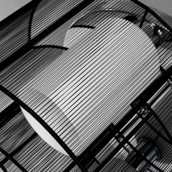 Black wire mesh canopy for semi-flush chandelier with fine vertical stripes and metal bars.