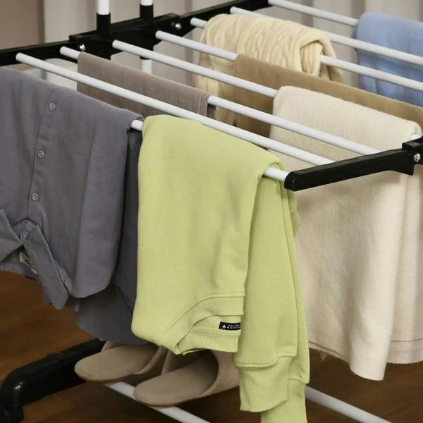 Side view of drying rack rails holding folded shirts and a green garment