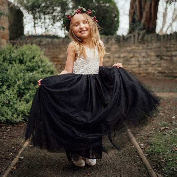 Young girl in a black and white dress with a floral headband outdoors.