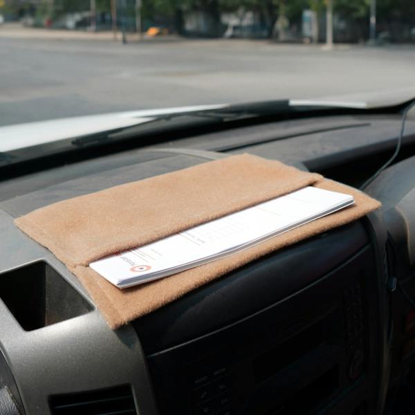 Beige storage pouch resting on a dashboard, featuring a soft texture and holding documents securely in place